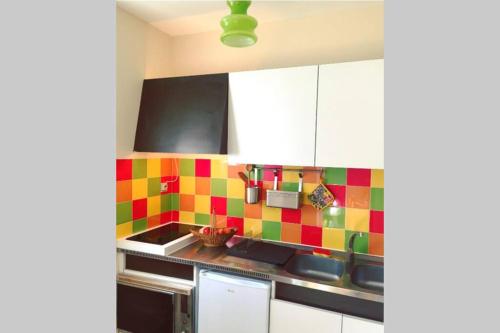 - une cuisine avec du carrelage coloré sur le mur dans l'établissement Les Lavandières, à Vernet-les-Bains