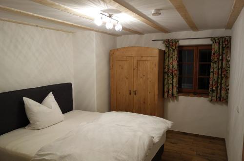 Schlafzimmer mit einem weißen Bett und einem Holzschrank in der Unterkunft Appartement - Ferienwohnung - FeWo Obernkammer in Emmering