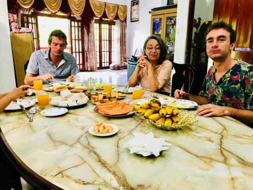 een groep mensen die rond een tafel zitten met eten bij Jenushi homestay in Kandy