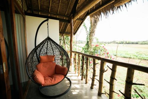a swing hanging from a porch with a view of a field at Fox & The Firefly Cottages in Loboc