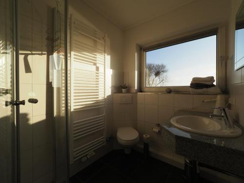 baño con lavabo y aseo y ventana en Haus Rungholt, en Nordstrand