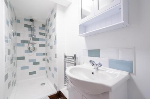 een witte badkamer met een wastafel en een douche bij The Brewery lodge in Cirencester