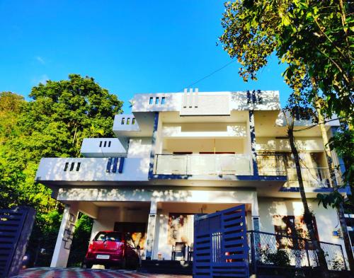 a building with a car parked in front of it at Nandana's Residency Munnar - A 4BHK Homestay for Indian Families in Munnar