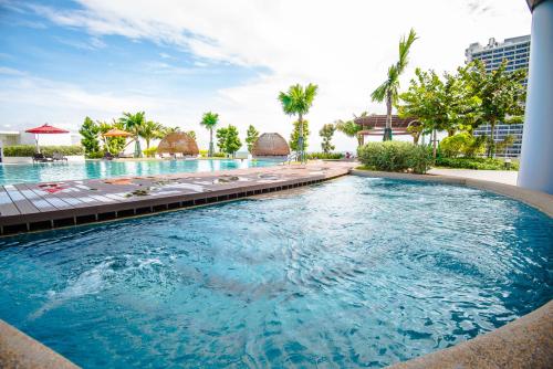 a swimming pool at a resort with chairs and palm trees at Stay @ Almas Puteri Harbour in Nusajaya