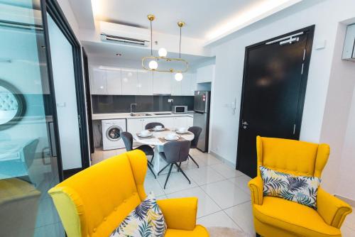 a kitchen and dining room with yellow chairs and a table at Stay @ Almas Puteri Harbour in Nusajaya