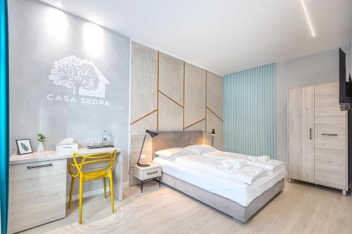 a bedroom with a bed and a desk and a yellow chair at Casa SEDRA in Braşov