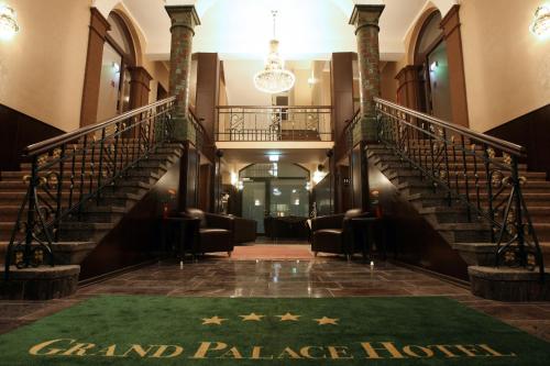 a lobby with stairs and a green rug on the floor at Grand Palace Hotel Hannover in Hannover