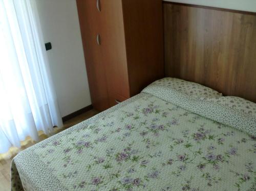 Dormitorio pequeño con cama con colcha de flores en Villa Berta, en Riva del Garda