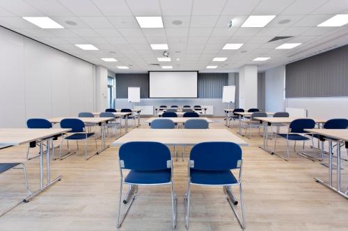 a conference room with tables and chairs and a screen at Hotel CONRAD Comfort in Kraków