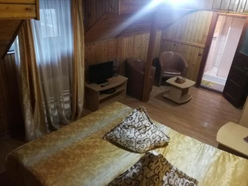 Habitación con cama, escritorio y TV. en Pensiunea Fara Nume, en Buşteni