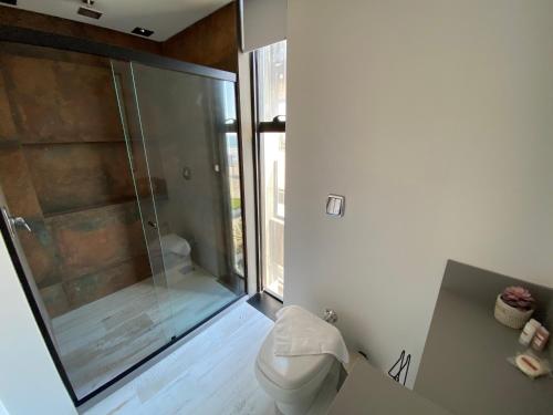 a bathroom with a toilet and a glass shower at BALUARTE POUSADA in Torres