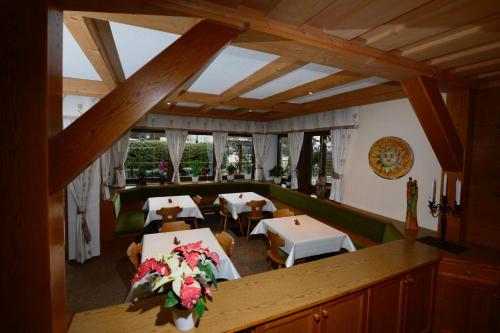 un comedor con mesas, sillas y ventanas en Appartements Sigmair, en Valdaora