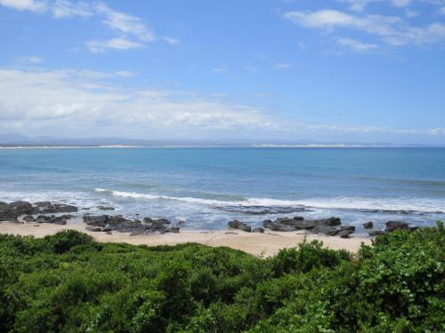 a beach with some rocks and the ocean at At the Beach in Jeffreys Bay