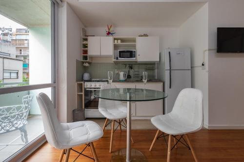 a kitchen with a glass table and white chairs at Estudio en lo mejor de Palermo * Estilo y glamour * in Buenos Aires