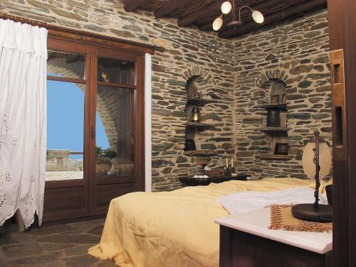 a bedroom with a stone wall with a bed and a window at Anastasia Luxury Villas in Gavrio