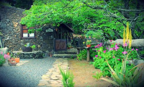 un jardin fleuri et une maison en pierre dans l'établissement CASA MARY LOLA, à Tiñor