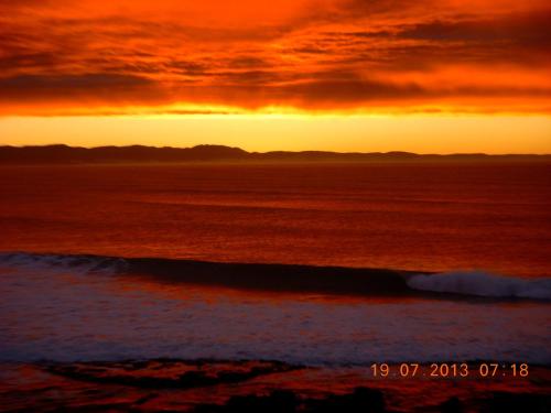 a sunset on the beach with the ocean at At the Beach in Jeffreys Bay
