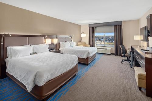 a hotel room with two beds and a desk at Holiday Inn Owensboro Riverfront by IHG in Owensboro