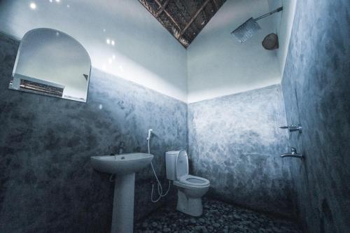 W łazience znajduje się umywalka, toaleta i lustro. w obiekcie Mermaid Cabana and Tree Houses w Tangalli