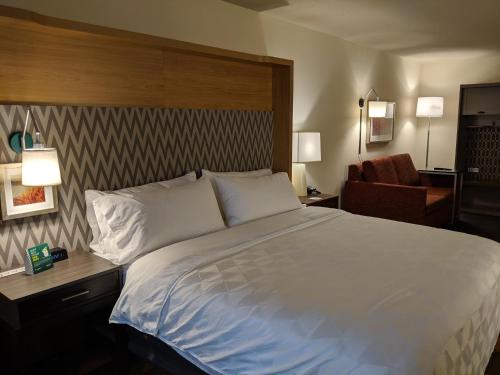 a bedroom with a large white bed and a chair at Holiday Inn Champaign, an IHG Hotel in Champaign