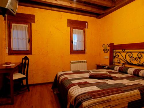 a bedroom with a bed and a table and windows at La Casona del Herrero in Navaleno