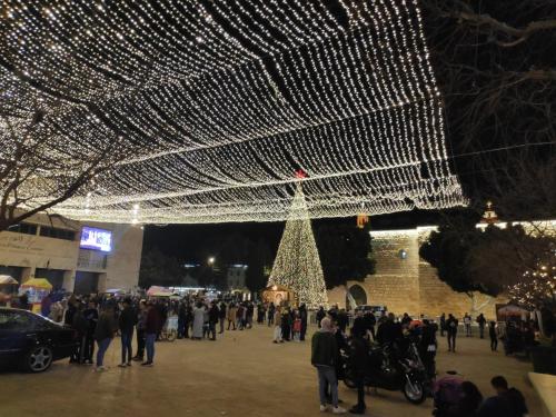 a crowd of people standing around a christmas tree at Dar Jacaman - In the heart of Bethlehem old city in Bethlehem