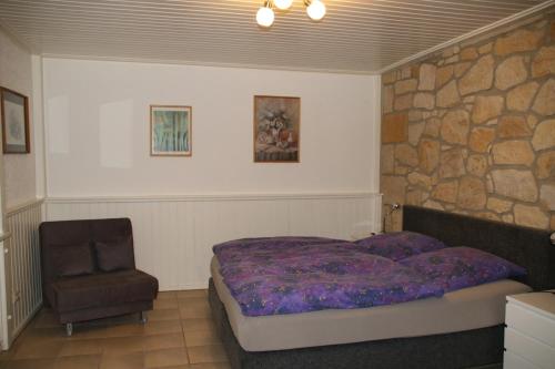 a bedroom with a bed and a chair at Ferienwohnung Am Heidelberg in Blankenburg