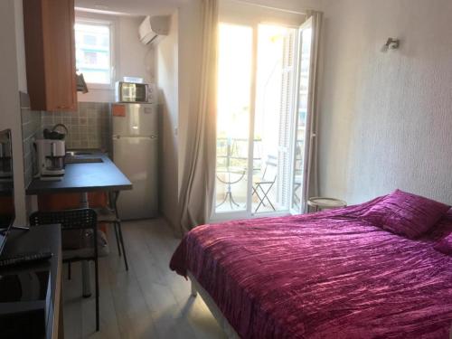 a bedroom with a bed and a table and a kitchen at chez Eva in Nice