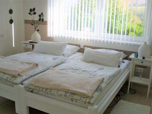two white beds in a room with a window at Seniorengerechte Ferienwohnung in Großalmerode in Trubenhausen