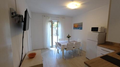 ein Wohnzimmer mit einem weißen Tisch und eine Küche in der Unterkunft Apartments Andreja in Pag