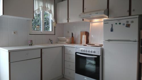 a white kitchen with a stove and a refrigerator at 2-bed maisonette in pine forest, 250m from beach between Skala Fourka and Siviri in Skála Foúrkas