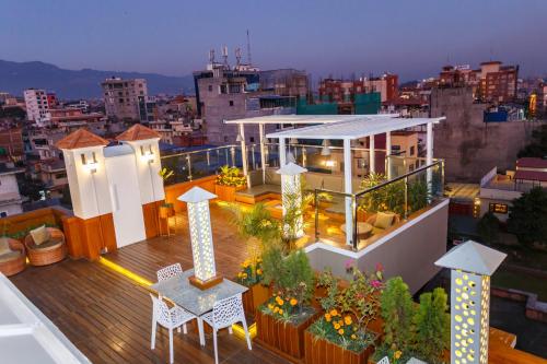 a rooftop deck with tables and chairs on a building at Feel Like Home Nepal in Kathmandu