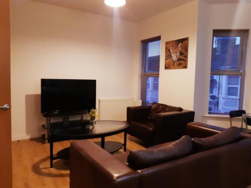 a living room with couches and a tv and a table at Yarmouth Apartments, Street Permit Parking, Close To Everything, Beach, Pier, Free WIFI in Great Yarmouth