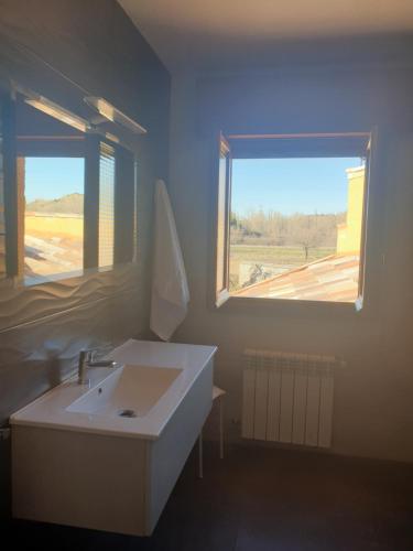 a bathroom with a white sink and two windows at Casa Rural El Caz in Trillo