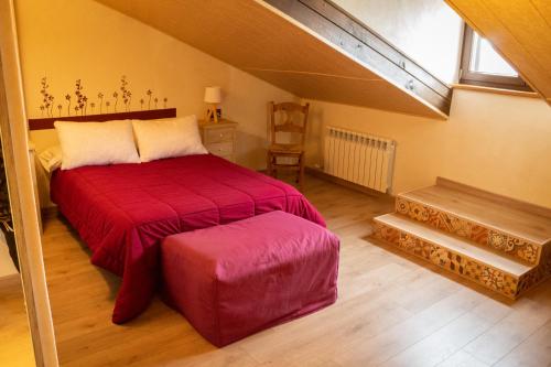 a bedroom with a red bed in a attic at Casa Rural Castil de Cabras in San Miguel de Valero