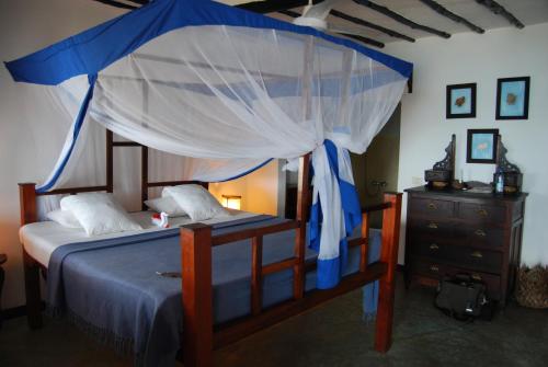 a bedroom with a canopy bed and a dresser at Chapwani Private Island in Grave Island