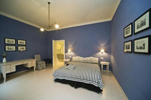 a bedroom with blue walls and a bed and a desk at Palazzo Dalla Rosa Prati in Parma