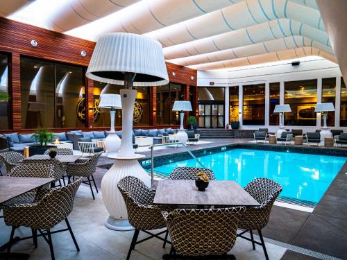 eine Hotellobby mit einem Pool, Tischen und Stühlen in der Unterkunft Hotel Arts in Calgary