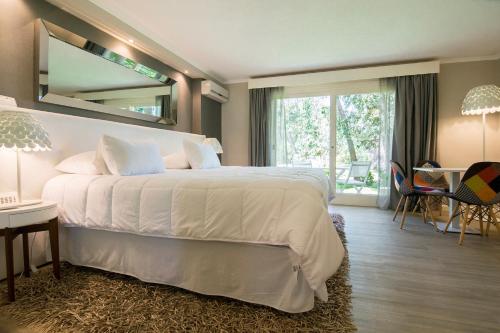 ein Schlafzimmer mit einem großen weißen Bett und einem großen Spiegel in der Unterkunft Punta del Este, Forest Lagoon, Luxury in Punta del Este