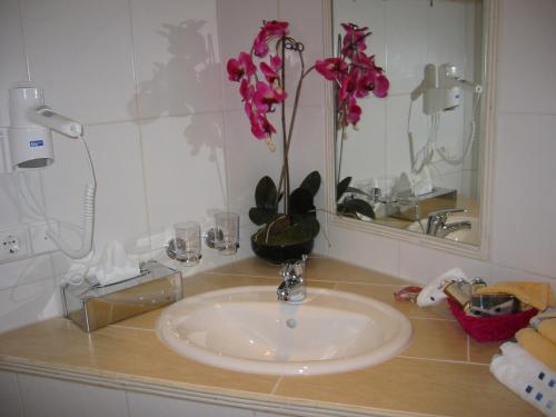 a bathroom sink with a vase with flowers on it at Cleo´s Hotel Kallstadt in Kallstadt