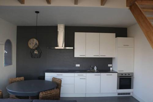 a kitchen with white cabinets and a table in it at Mooi appartement in een prachtige fiets-wandelomgeving in Abcoude