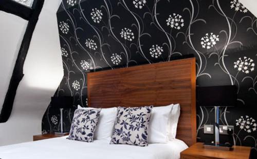 a bedroom with a bed with a black and white wall at The Boleyn Hotel in Staines