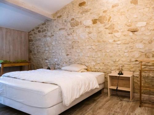 La Baume-CornillaneにあるL'abondanceの白いベッドと石の壁が備わるベッドルーム1室