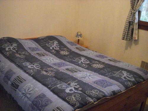 a bed with a blue and white blanket on it at Camping de la Pelouse in Jaulny
