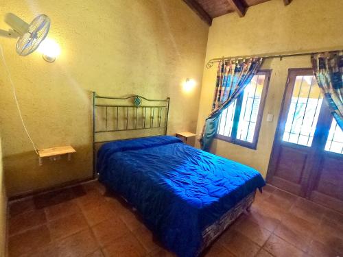a bedroom with a bed with a blue comforter at Casa de Veraneo en Villa La Bolsa in Villa Anizacate