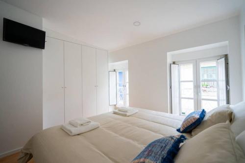 a white bedroom with a large bed with two towels at Sé with Love- Sinta Braga como ela é. in Braga