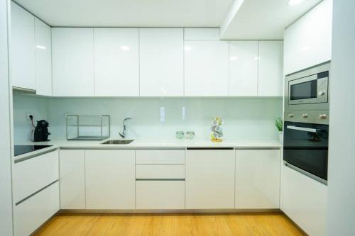 a white kitchen with white cabinets and a microwave at Sé with Love- Sinta Braga como ela é. in Braga