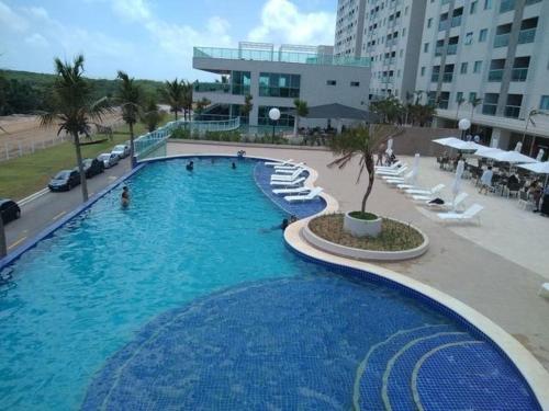 una gran piscina con sillas blancas y un edificio en Salinas Park Resort - Apartamento inteiro Frente Mar, en Salinópolis