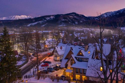 a town in the snow at night with mountains at Serce Tatr Residence Zakopane - blisko Krupówek in Zakopane