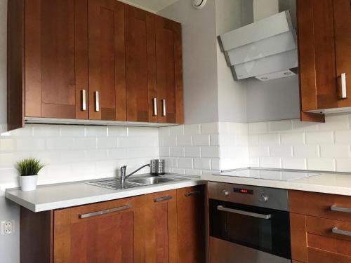 una cocina con armarios de madera y fregadero en Apartament Morska en Gdynia